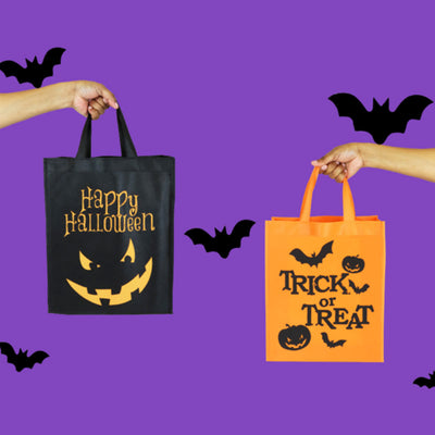 Two Halloween-themed tote bags held by hands against a purple background with bats.